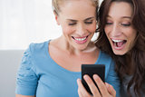 Cheerful friends reading message on their phone