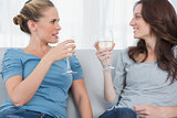 Women clinking their wine glasses while sitting on the sofa