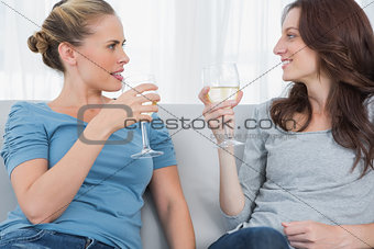 Women clinking their wine glasses while sitting on the sofa