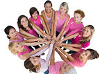 Cheerful women joined in a circle and looking up at camerawearing pink for breast cancer