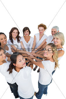 Happy female models joining hands in a circle and looking at camera