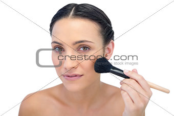 Gorgeous natural model applying makeup on her face