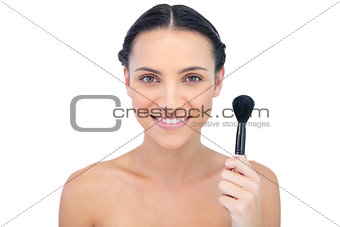 Cheerful natural model holding powder brush