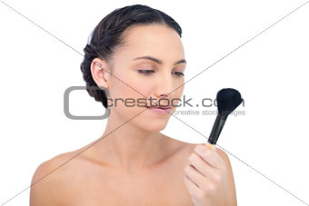 Natural model holding and looking at her powder brush