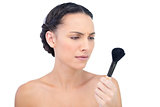 Serious natural model holding and looking at her powder brush