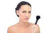 Serious natural model holding a powder brush