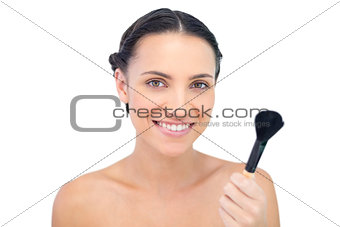 Smiling natural model holding a powder brush