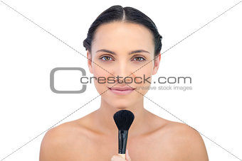 Peaceful natural model holding a makeup brush