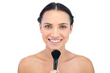 Smiling natural model holding a makeup brush