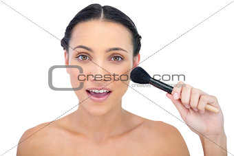 Smiling natural brunette applying powder