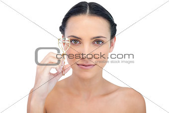 Smiling natural brunette holding eyelash curler