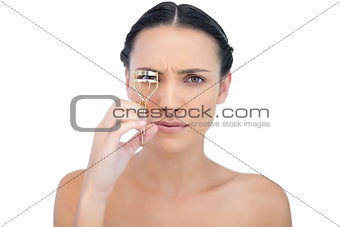 Serious natural brunette with eyelash curler