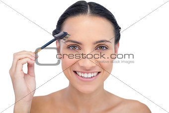 Cheerful young model using eyebrow brush