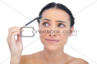 Curious young model using eyebrow brush
