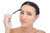 Uneasy young model using eyebrow brush