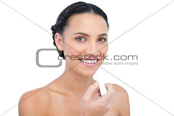 Smiling young natural model applying chap stick
