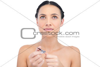 Pensive young model using nail clippers