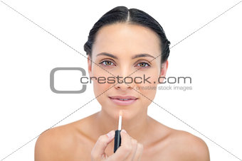Relaxed young brunette applying lip gloss