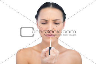 Serious young model holding natural lip gloss