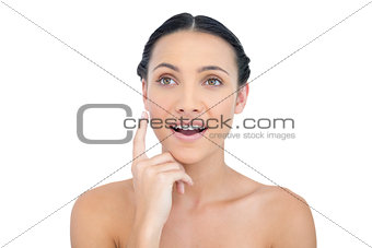 Astonished nude model posing finger on her cheek