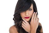 Glamorous brunette with red lips posing touching her face