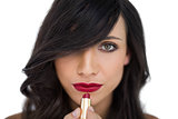 Glamorous brunette applying red lipstick