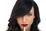 Sensual brunette applying red lipstick