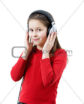 A smiling child girl listens to music through headphones
