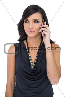 Elegant brown haired model with black classy clothes posing holding smartphone