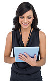 Smiling elegant brown haired model typing on tablet