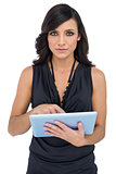 Serious elegant brown haired model scrolling on tablet pc