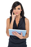 Pensive elegant brown haired model holding tablet