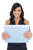 Happy elegant brown haired model holding tablet in front of her