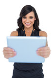 Happy elegant brown haired model looking at her tablet pc