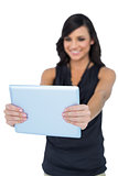 Smiling elegant brown haired model looking at her tablet pc
