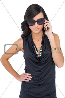 Serious elegant brunette wearing sunglasses on the phone