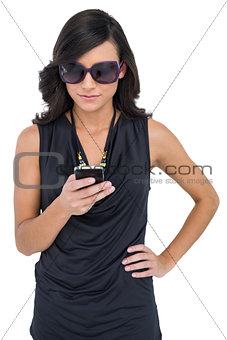 Concentrated elegant brunette wearing sunglasses texting