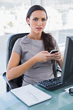 Worried gorgeous businesswoman texting on her smartphone