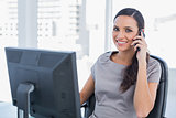 Cheerful dark haired businesswoman having a phone conversation