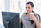 Attractive businesswoman holding coffee and working