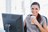 Attractive businesswoman drinking coffee and cheering at camera