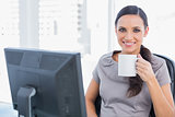 Cheerful attractive businesswoman drinking tea