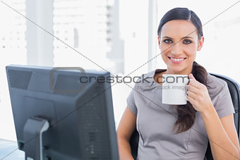 Cheerful attractive businesswoman drinking tea