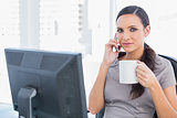 Relaxed businesswoman holding her coffee and phone
