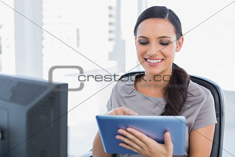 Cheerful attractive secretary scrolling on tablet pc