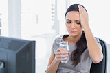 Attractive secretary with headache holding water and touching her head