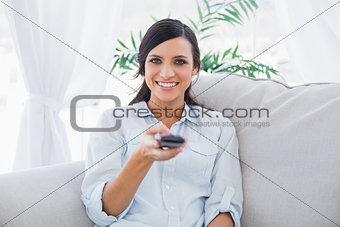 Smiling attractive brunette holding remote