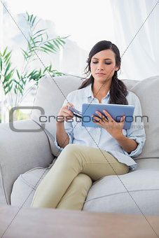 Concentrated attractive brunette using her credit card to buy online
