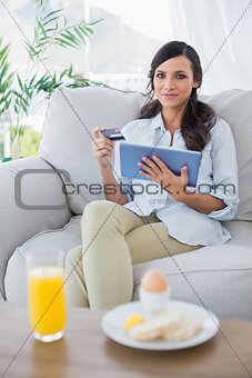 Peaceful brunette using her credit card to buy online