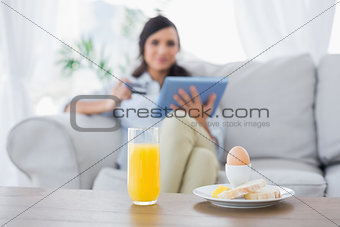 Peaceful brunette having breakfast while buying online